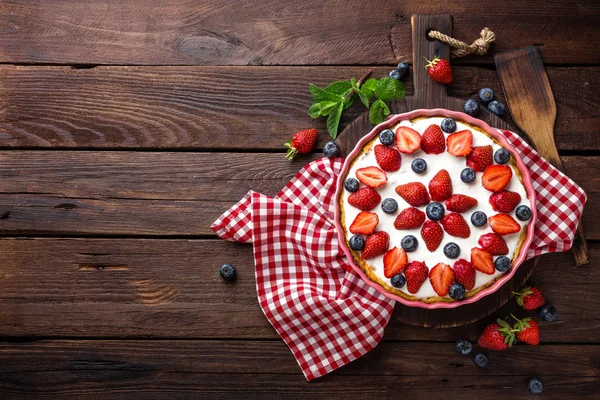 Heerlijke aardbei taart met verse bosbessen en slagroom op houten rustieke tafel, cheesecake, bovenaanzicht — Stockfoto