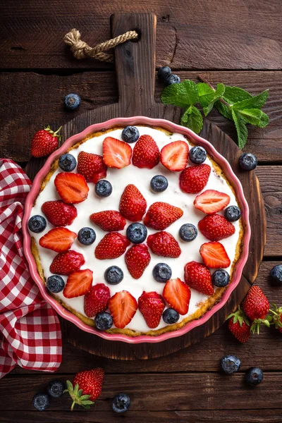 Läckra jordgubbs paj med färska blåbär och vispad grädde på rustika träbord, cheesecake, ovanifrån — Stockfoto