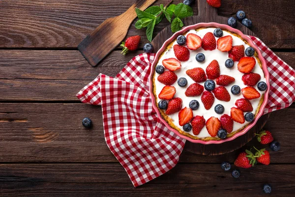 美味的草莓馅饼加新鲜的蓝莓和搅打的奶油木仿古桌、 芝士蛋糕、 顶视图 — 图库照片