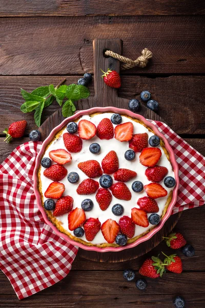 Köstliche Erdbeerkuchen mit frischen Blaubeeren und Schlagsahne auf rustikalem Holztisch, Käsekuchen, Draufsicht — Stockfoto