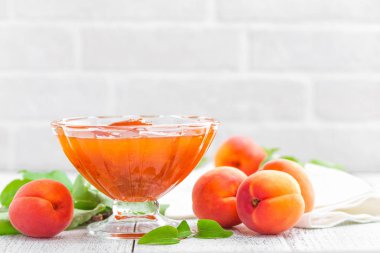 Kayısı reçeli ve Beyaz ahşap masa yapraklarda ile taze meyve