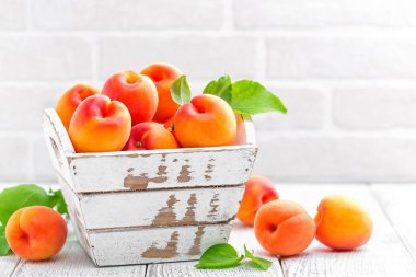 Beyaz ahşap zemin üzerinde yaprakları ile taze kayısı