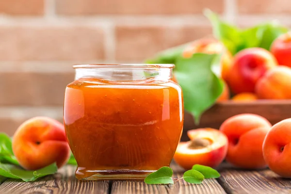Apricot jam in a jar and fresh fruits with leaves — Stock Photo, Image