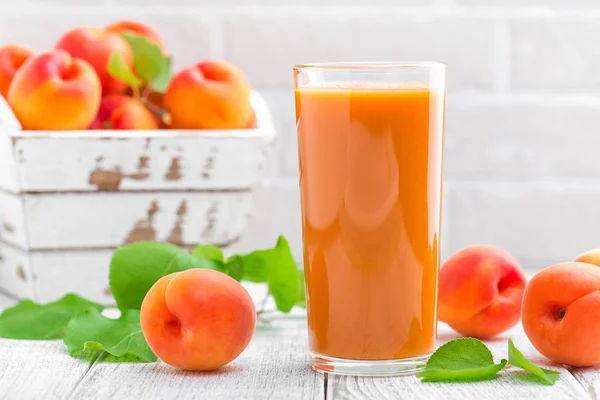 Aprikos juice och färsk frukt med blad — Stockfoto