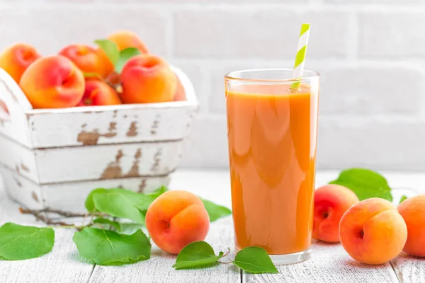Aprikosensaft und frische Früchte mit Blättern — Stockfoto