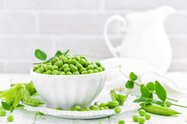 Beyaz arkaplanda yaprakları olan yeşil bezelyeler