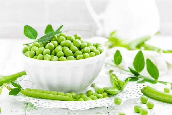 Guisantes verdes con hojas sobre fondo blanco —  Fotos de Stock