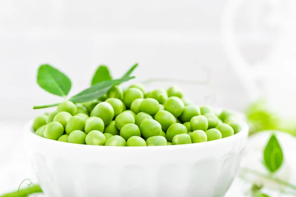 Groene erwten met bladeren op witte achtergrond — Stockfoto