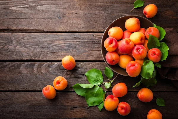 Fresh apricots with leaves on wooden table — Stock Photo, Image