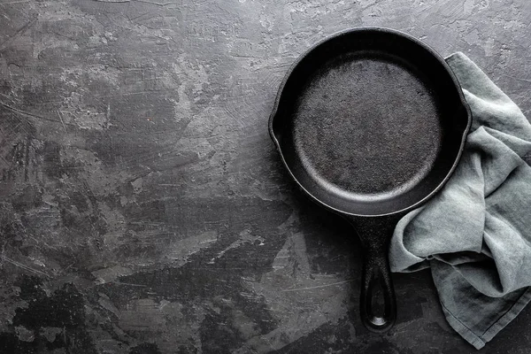 Lege gietijzeren koekenpan op donkere grijze culinaire achtergrond, van bovenaf bekijken — Stockfoto