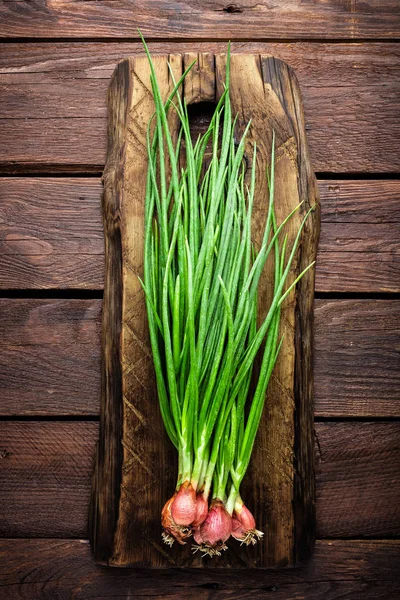 Cipolla verde o scalogno su tavola di legno, erba cipollina fresca primaverile — Foto Stock