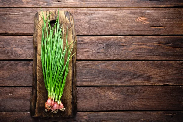 Cebolla verde o cebolleta en tabla de madera, cebolletas frescas de primavera —  Fotos de Stock