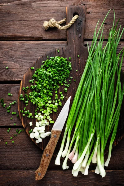 Grüne Zwiebel oder Schalotte auf Holzbrett, frischer Frühlingsschnittlauch — Stockfoto