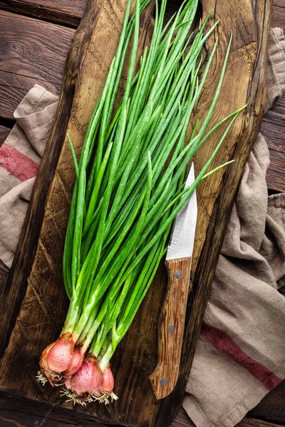 Cebolla verde o cebolleta en tabla de madera, cebolletas frescas de primavera —  Fotos de Stock