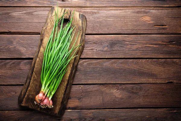 Cipolla verde o scalogno su tavola di legno, erba cipollina fresca primaverile — Foto Stock