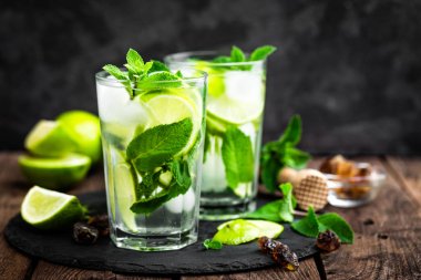 Nane kokteyli mojito 'yu rom ve limonla tazelemek, soğuk içecek veya siyah arka planda buzlu içecek.