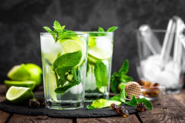 Nane kokteyli mojito 'yu rom ve limonla tazelemek, soğuk içecek veya siyah arka planda buzlu içecek.