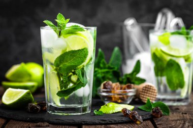 Nane kokteyli mojito 'yu rom ve limonla tazelemek, soğuk içecek veya siyah arka planda buzlu içecek.