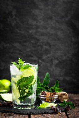Nane kokteyli mojito 'yu rom ve limonla tazelemek, soğuk içecek veya siyah arka planda buzlu içecek.