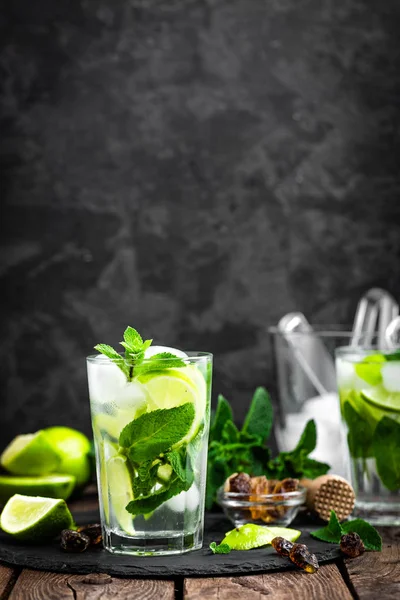 Refrescante cóctel de menta mojito con ron y lima, bebida fría o bebida con hielo sobre fondo negro —  Fotos de Stock