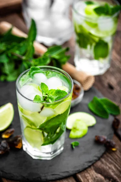 Refreshing mint cocktail mojito with rum and lime, cold drink or beverage with ice on black background — Stock Photo, Image