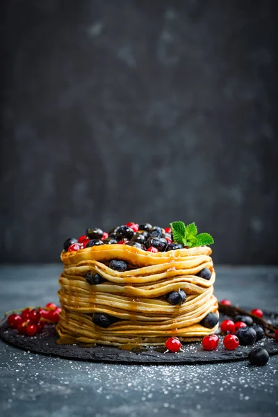 Млинці зі свіжими ягодами та кленовим сиропом на темному фоні, крупним планом — стокове фото