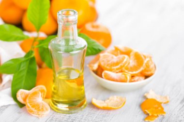 Mandalina yaprakları ve beyaz bir arka plan üzerinde temel narenciye petrol şişe ile
