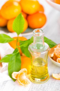 Mandalina yaprakları ve beyaz bir arka plan üzerinde temel narenciye petrol şişe ile