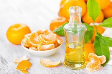 Mandalina yaprakları ve beyaz bir arka plan üzerinde temel narenciye petrol şişe ile