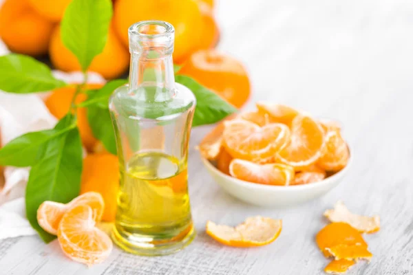 Tangerines aux feuilles et bouteille d'huile essentielle d'agrumes sur fond blanc — Photo