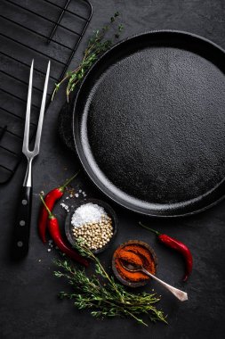 Siyah arka planda, üstten görünüm yemek pişirmek için malzemeler ile boş dökme demir tava