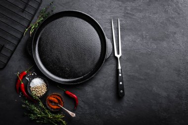 Empty cast-iron pan with ingredients for cooking on black background, top view clipart