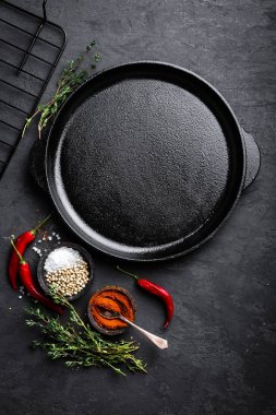 Siyah arka planda, üstten görünüm yemek pişirmek için malzemeler ile boş dökme demir tava