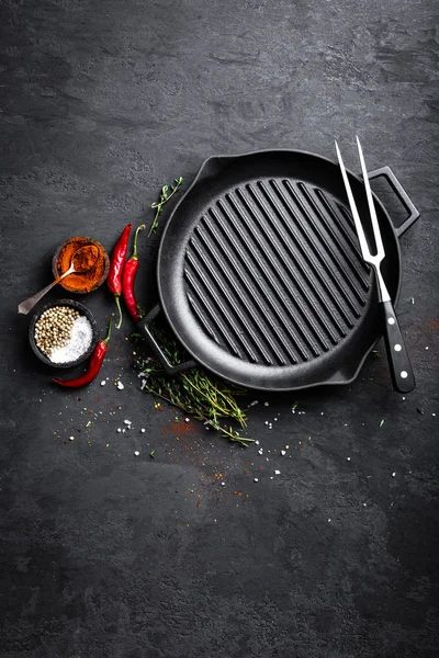 Siyah arka planda, üstten görünüm yemek pişirmek için malzemeler ile boş dökme demir ızgara tava