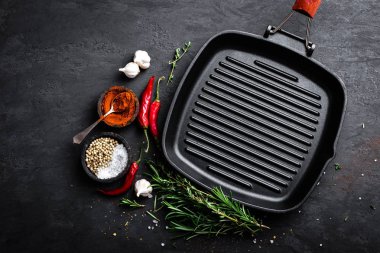 Siyah arka planda, üstten görünüm yemek pişirmek için malzemeler ile boş dökme demir ızgara tava