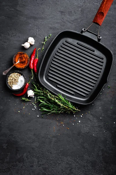 Siyah arka planda, üstten görünüm yemek pişirmek için malzemeler ile boş dökme demir ızgara tava
