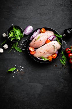 Taze çiğ tavuk eti, baharat, soğan ve domates siyah arka plan üzerinde Marine fileto. Üstten Görünüm