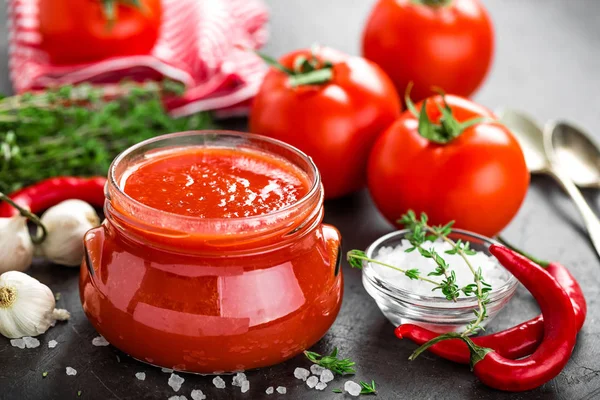 トマト ペースト ガラスの瓶 暗い背景の上に新鮮なトマトのピューレします 唐辛子とトマト野菜のホットソース — ストック写真