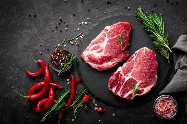 Çiğ domuz eti. Siyah arka planda taze biftekler. Üst görünüm
