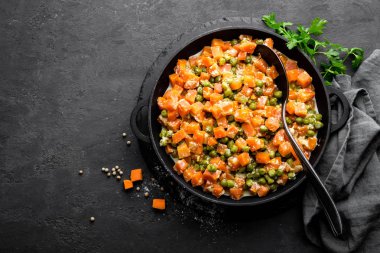 Kremalı süt sos güveç, siyah arka plan, üstten görünüm üzerinde sebze sote taze yeşil bezelye ile havuç kızarmış