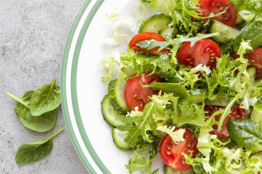 Taze domates, salatalık, ıspanak, frize ve susam plaka üzerinde sağlıklı sebze salatası. Diyet menüsü. Üstten Görünüm.
