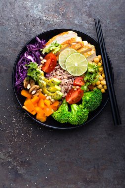 Buda kase tabak tavuk fileto, kahverengi pirinç, avakado, biber, domates, brokoli, kırmızı lahana, nohut, taze marul salatası, çam fıstığı ve ceviz. Sağlıklı yemek dengeli. Üstten Görünüm