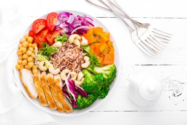 Buda kase tabak tavuk fileto, kahverengi pirinç, biber, domates, brokoli, soğan, nohut, taze marul salatası, kaju ve ceviz. Sağlıklı yemek dengeli. Üstten Görünüm. Beyaz arka plan