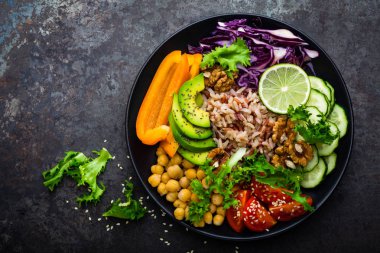 Buddha bowl dish with brown rice, avocado, pepper, tomato, cucumber, red cabbage, chickpea, fresh lettuce salad and walnuts. Healthy vegetarian eating, super food. Top view clipart