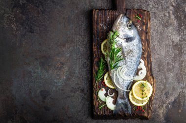 Taze malzemelerle ahşap tahta üzerinde yemek pişirmek için dorado balık. Ham çipura veya dorada balık karanlık vintage metal arka plan üzerinde. Diyet yiyecek. Üstten Görünüm