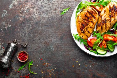 Izgara tavuk göğsü. Kızarmış tavuk fileto ve taze sebze salatası domates, salatalık ve roka yaprakları. Salatalı tavuk eti. Sağlıklı yiyecekler. Düz yatıyordu. Üst Manzara. Koyu arkaplan