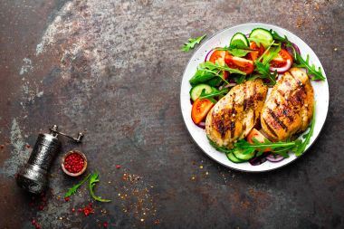 Izgara tavuk göğsü. Kızarmış tavuk fileto ve taze sebze salatası domates, salatalık ve roka yaprakları. Salatalı tavuk eti. Sağlıklı yiyecekler. Düz yatıyordu. Üst Manzara. Koyu arkaplan