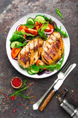Izgara tavuk göğsü. Kızarmış tavuk fileto ve taze sebze salatası domates, salatalık ve roka yaprakları. Salatalı tavuk eti. Sağlıklı yiyecekler. Düz yatıyordu. Üst Manzara. Koyu arkaplan