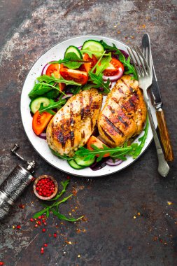 Izgara tavuk göğsü. Kızarmış tavuk fileto ve taze sebze salatası domates, salatalık ve roka yaprakları. Salatalı tavuk eti. Sağlıklı yiyecekler. Düz yatıyordu. Üst Manzara. Koyu arkaplan