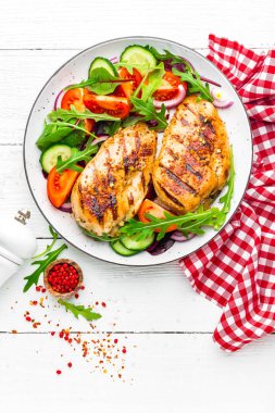 Izgara tavuk göğsü. Kızarmış tavuk fileto ve taze sebze salatası, domates, salatalık ve roka yaprakları. Tavuk et salatası. Sağlıklı gıda. Düz yatıyordu. Üstten Görünüm. Beyaz arka plan